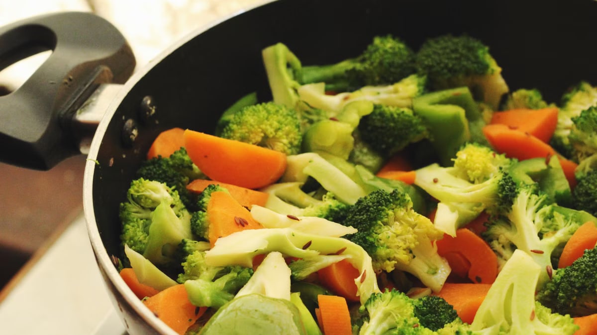 A vibrant mix of broccoli, carrots, and peppers cooking in a pan.
