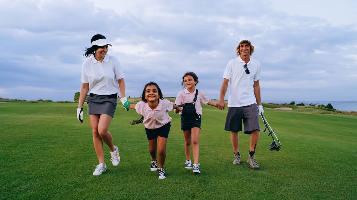 A happy family walking together on a lush golf course, enjoying a sunny day.