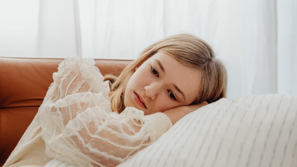 A thoughtful teenage girl lying on a sofa, reflecting emotions and calm demeanor.